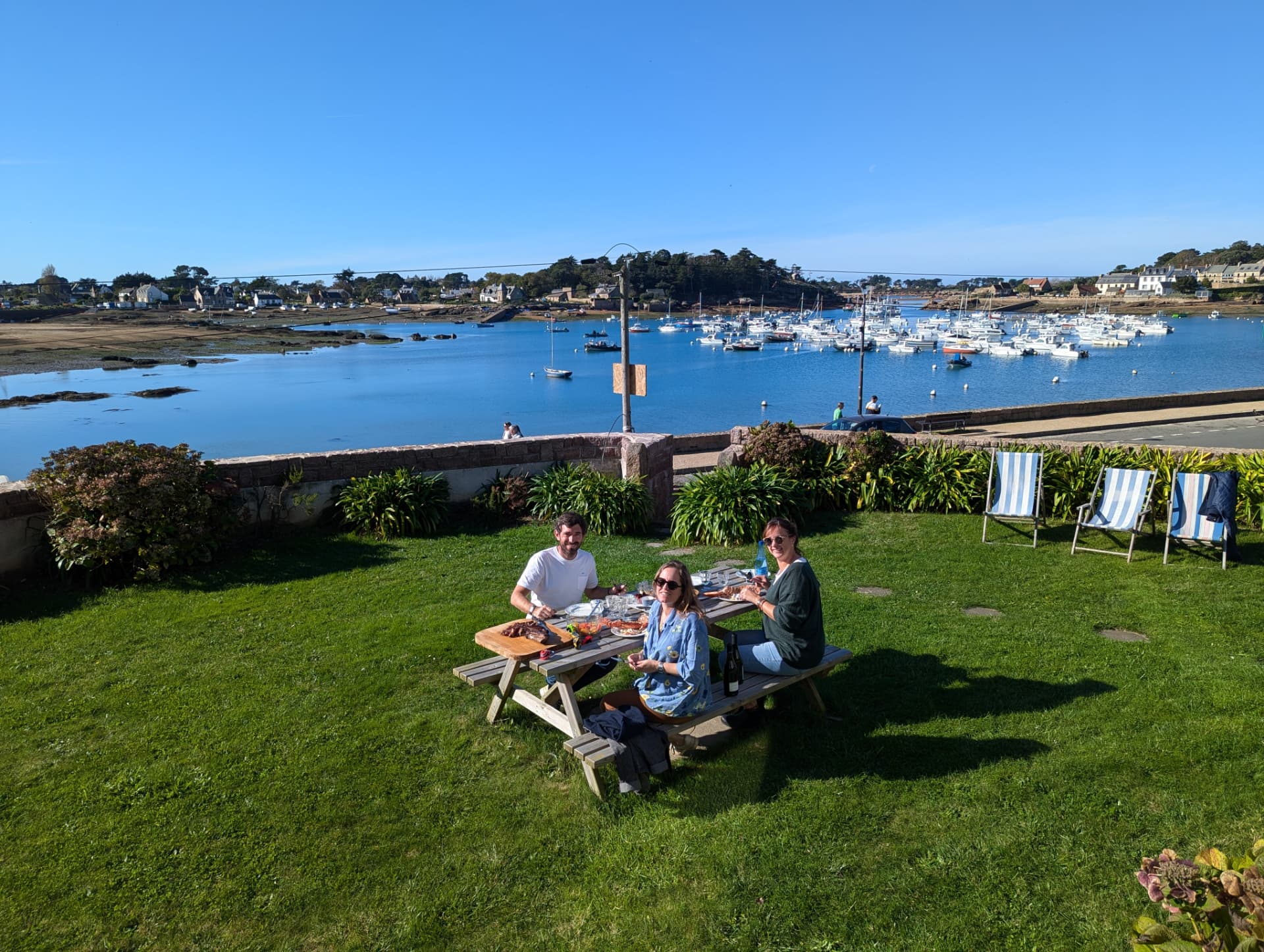Les amis déjeunent dans le jardin face au port